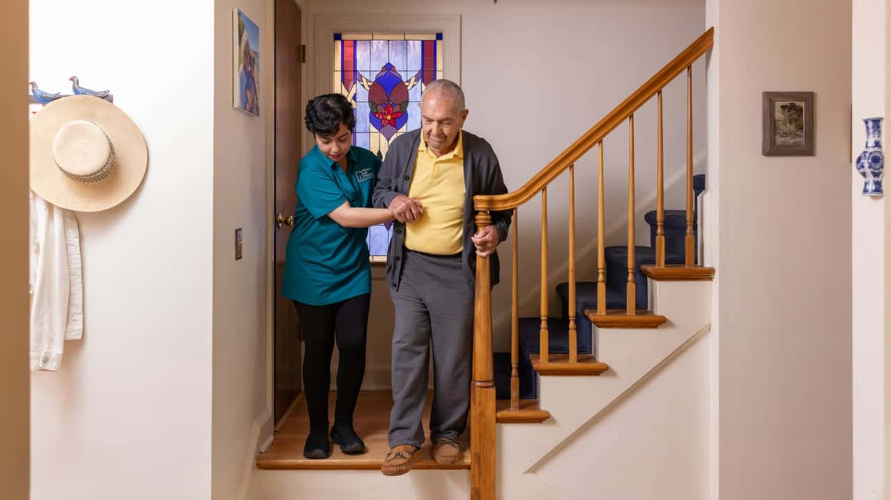 How Right at Home Evolved and Set New Standards Photo of Right at Home caregiver and client descending stairs